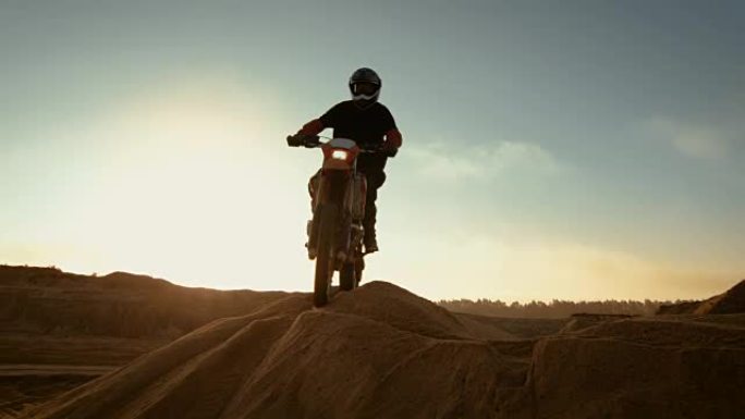 专业摩托车越野赛摩托车骑手在沙丘和越野车道上行驶。这是《日落》，赛道上布满了烟雾。