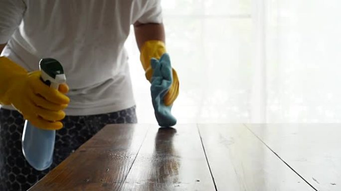 清洁剂的手通过喷雾清洁木桌并用超细纤维布擦拭