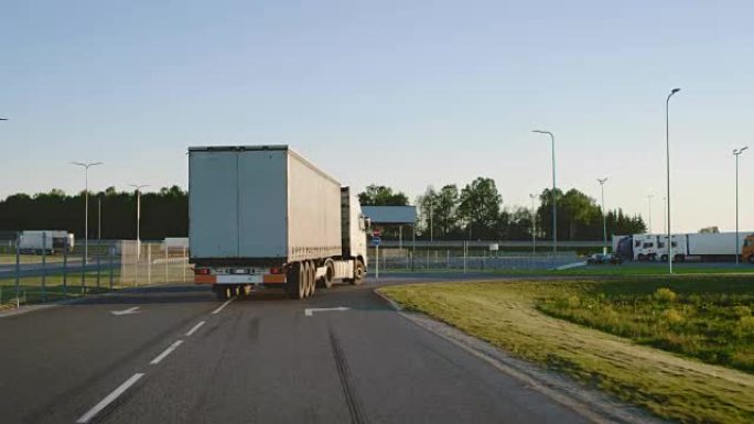 半卡车的后续镜头，货物拖车在高速公路上左转。卡车移至卸货仓库区域。