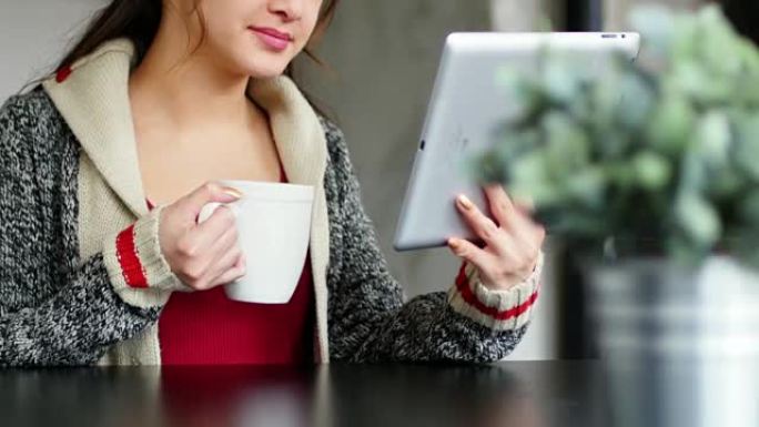 使用数字平板电脑时喝咖啡的女人