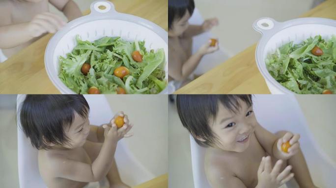 4k手持，男婴在沙拉碗里吃西红柿。