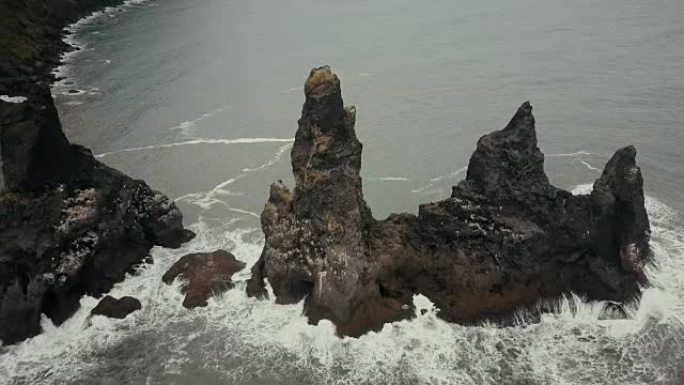 冰岛的山魔脚趾鸟瞰海鸥巢。直升机在黑海滩上的悬崖上飞来飞去