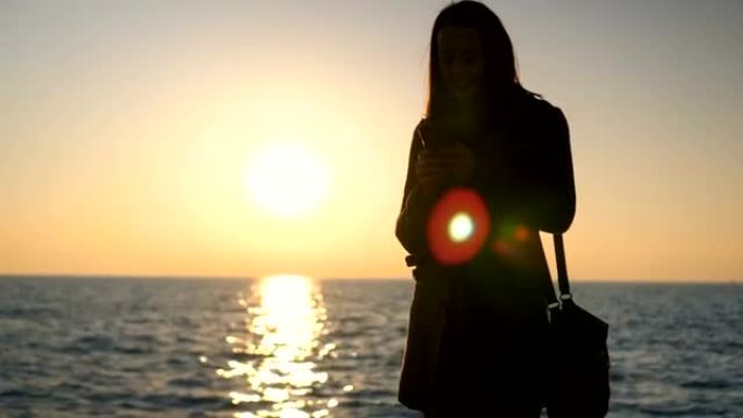 女人在海边日落时发短信