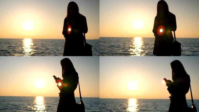 女人在海边日落时发短信