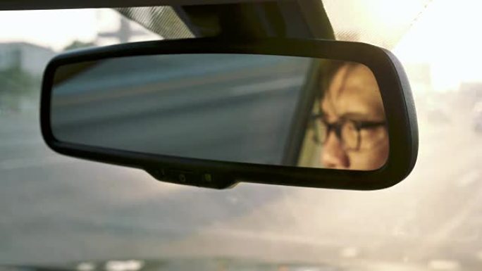 在行驶中的汽车，交通中，亚洲男子脸在后视镜中的反射