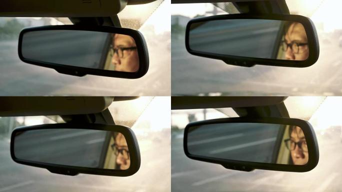 在行驶中的汽车，交通中，亚洲男子脸在后视镜中的反射