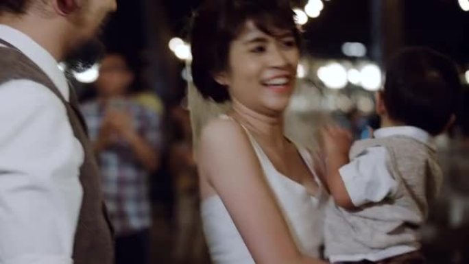 亚洲母亲在晚上的婚礼上抱着男婴。