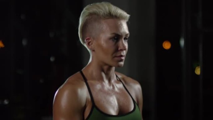 汗流浃背的女运动员站在黑暗的健身房