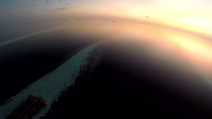 马尔代夫热带岛屿度假胜地海上日落和豪华水上别墅的鸟瞰图。