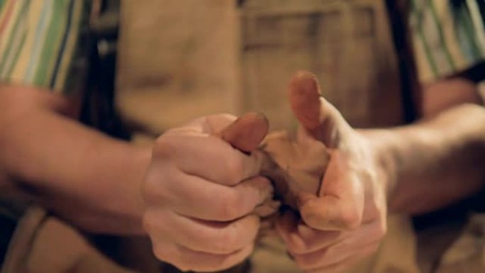 男性手指揉捏棕色粘土的特写视图。