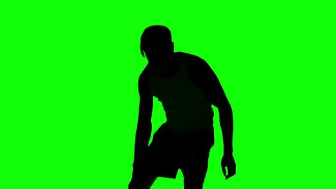 在绿色屏幕上玩篮子的男人的剪影