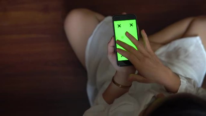 十几岁的女孩正在家里使用带有绿屏的智能手机