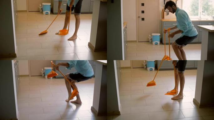 年轻人，丈夫在厨房扫地时用黄色扫帚闲逛。慢镜头，稳定镜头