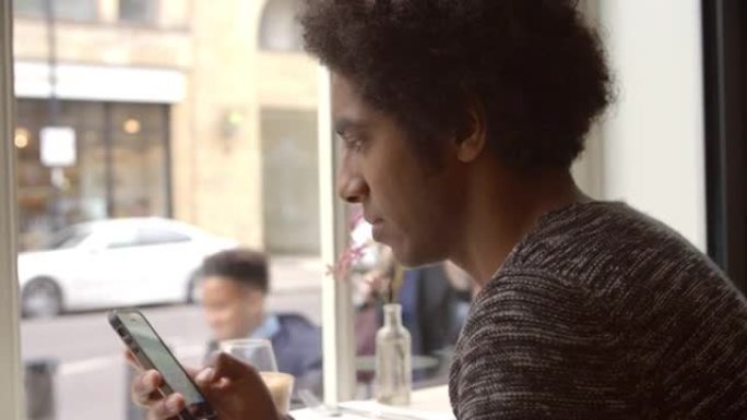 年轻人在咖啡馆使用手机更新社交媒体