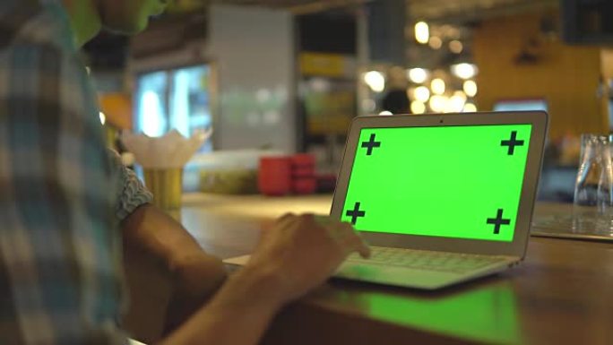 男子打字笔记本电脑键盘与绿屏显示器