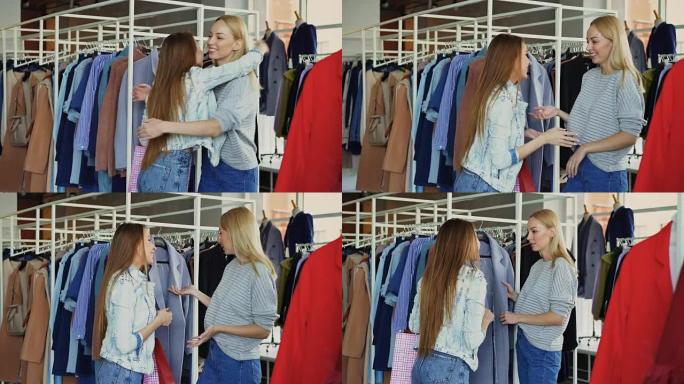 美丽的年轻女子正在商店里选择外套，并会见女性朋友。女孩们很高兴见到对方，她们拥抱着，笑着聊天。