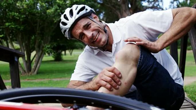摔倒的骑自行车的人抱着受伤的膝盖