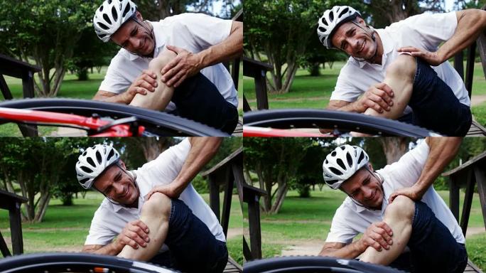 摔倒的骑自行车的人抱着受伤的膝盖