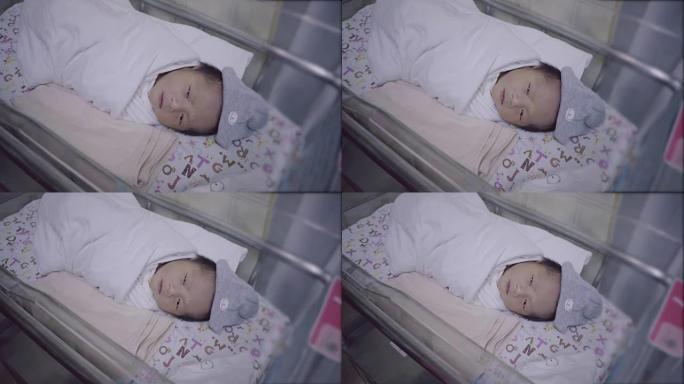 新生的亚洲婴儿用婴儿毯睡在孵化器里。