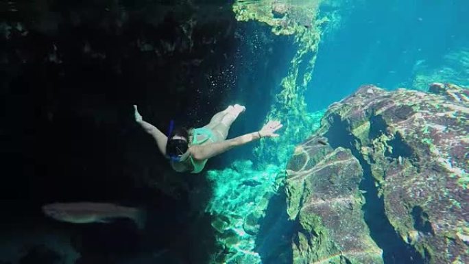 水下: 迷人的年轻女子在Gran Cenote探索洞穴自由潜水