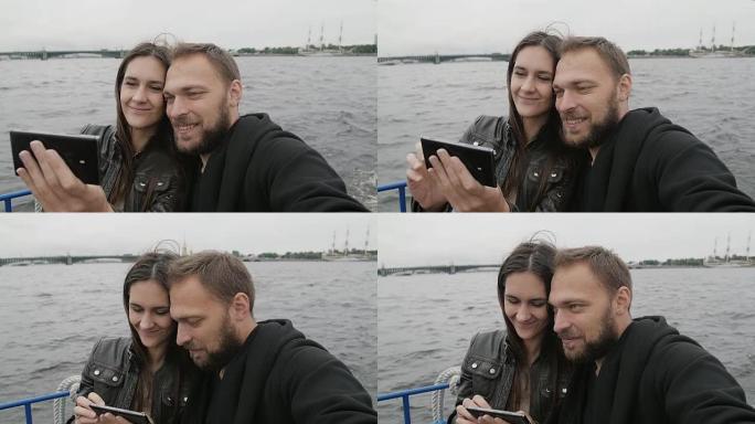 微笑的美丽夫妇使用智能手机，在河巴士上自拍。圣彼得堡观光，桥，慢莫