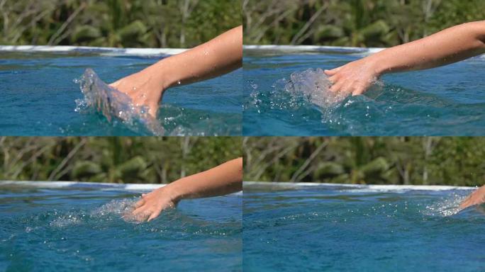 关闭女性手触摸水面溅水滴在游泳池和水疗度假村