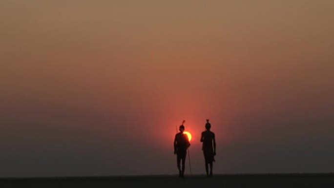 布须曼人在Makgadikgadi pan的夕阳下行走