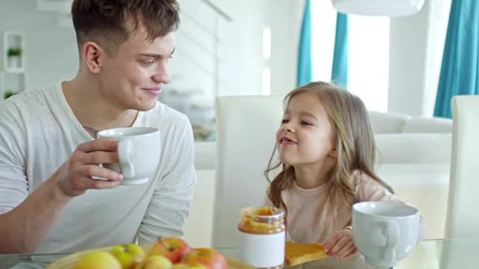 快乐的父亲和可爱的女儿在早餐时聊天