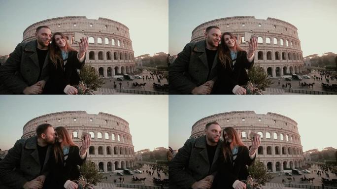幸福的年轻夫妇在意大利罗马竞技场附近自拍。英俊的男人亲吻女人，微笑