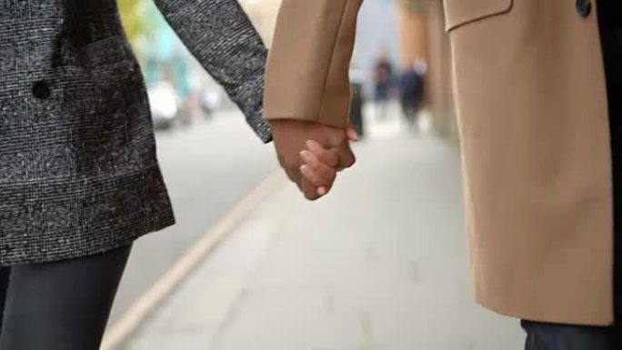 情侣手牵着手走在城市街道上的特写