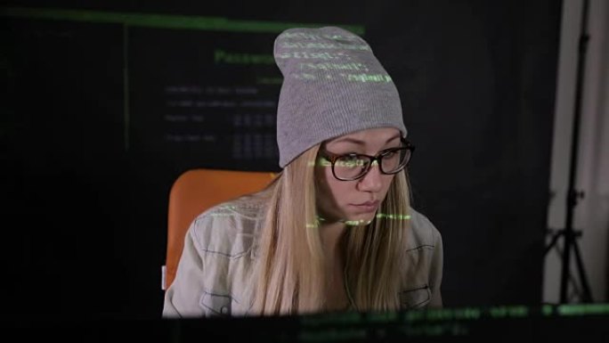 迷人的年轻女子晚上在黑暗的房间里使用电脑。计算机代码反映在她的脸上