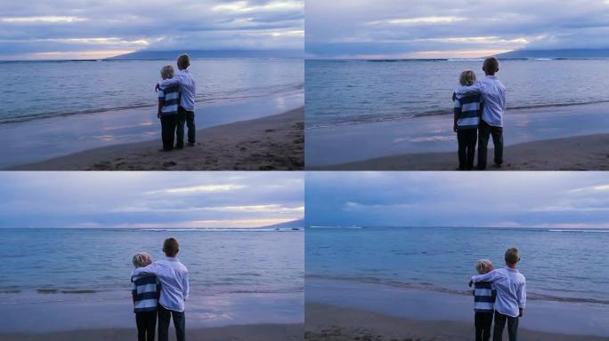 日落时，两个小男孩在海滩上摆姿势。