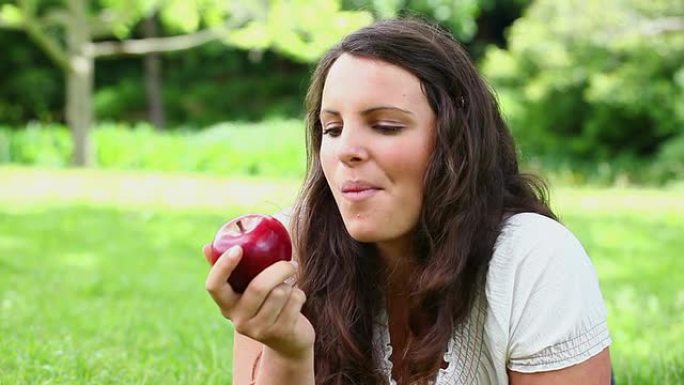 微笑的黑发女人吃红苹果