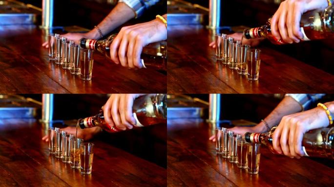 酒保在酒吧柜台将龙舌兰酒倒入小玻璃杯中