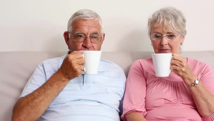 快乐的高级夫妇在沙发上喝咖啡