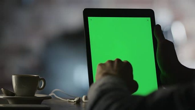 在咖啡馆中使用带有绿色屏幕的平板电脑在纵向模式下