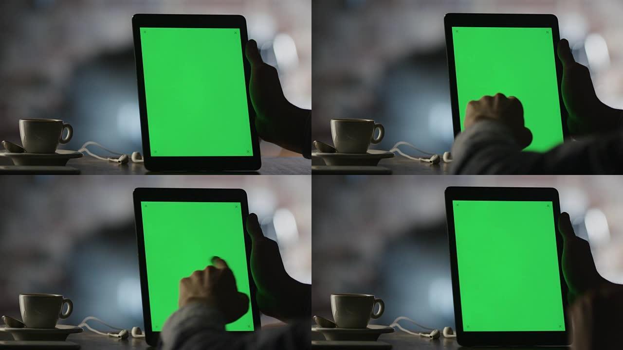 在咖啡馆中使用带有绿色屏幕的平板电脑在纵向模式下