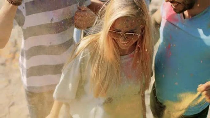 在印度教胡里节庆祝活动中，一个金发女孩向人群投掷彩色粉末的高角度镜头。在这个阳光明媚的日子里，他们玩
