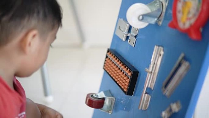 SLO MO亚洲男婴玩DIY忙碌的棋盘益智游戏。