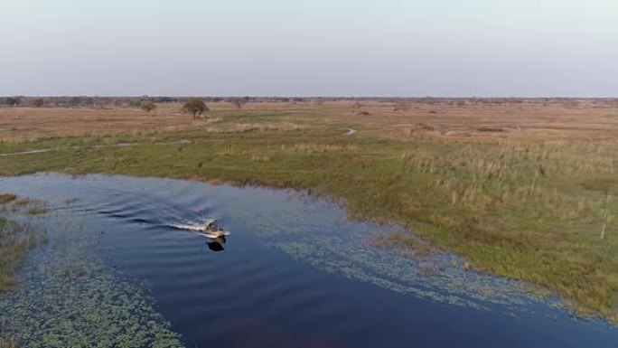 在奥卡万戈三角洲的水道上，一艘游船驶向相机的空中缩小视图