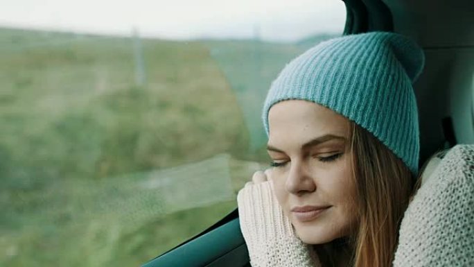 头上戴着冬帽的女人睡在汽车后座上