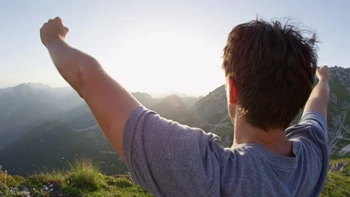 慢动作特写男性徒步旅行者举起双臂欣赏山顶的景色