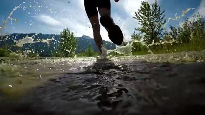 健康女性慢跑通过水坑4k的后视图