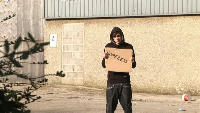 举着写着“无家可归”的牌子的青年/流氓