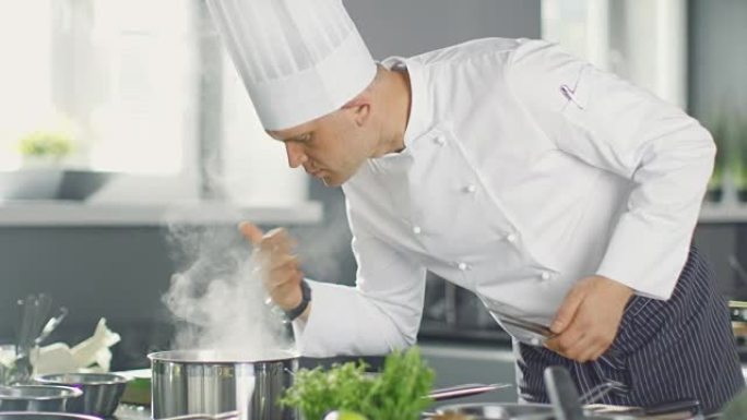 著名的餐厅厨师闻到了平底锅里的蒸汽。他在现代厨房里准备菜肴。