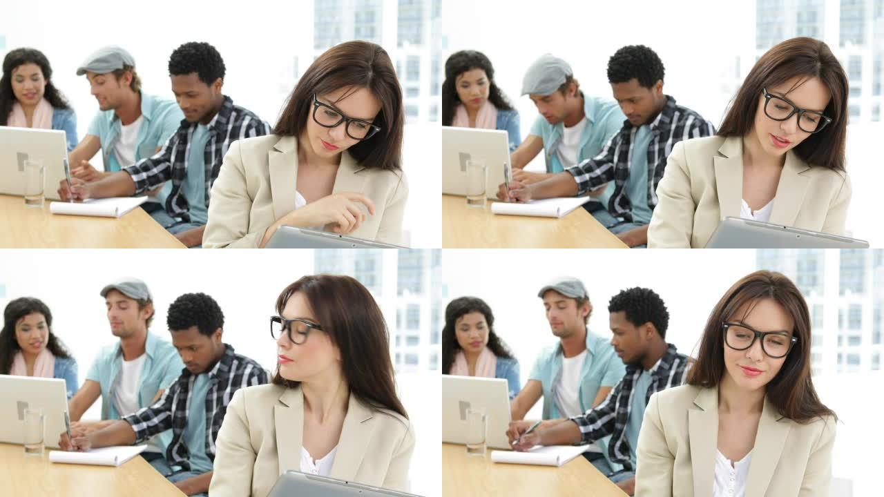 微笑的女人在同事背后工作时使用平板电脑