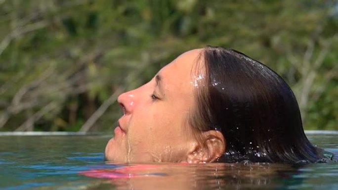 特写: 漂亮女人在游泳池潜水时从水中浮出水面