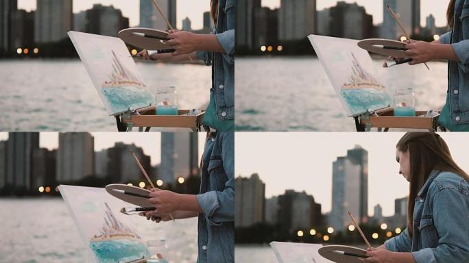 年轻女子在美国芝加哥的密歇根湖岸边画画。背景是市中心的灯光