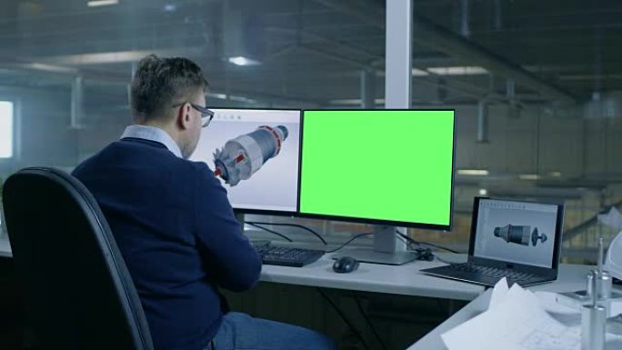 首席男工程师为一家大型工业公司设计3D涡轮/发动机，他的第二个显示屏显示了模拟绿屏计算机。从办公室窗