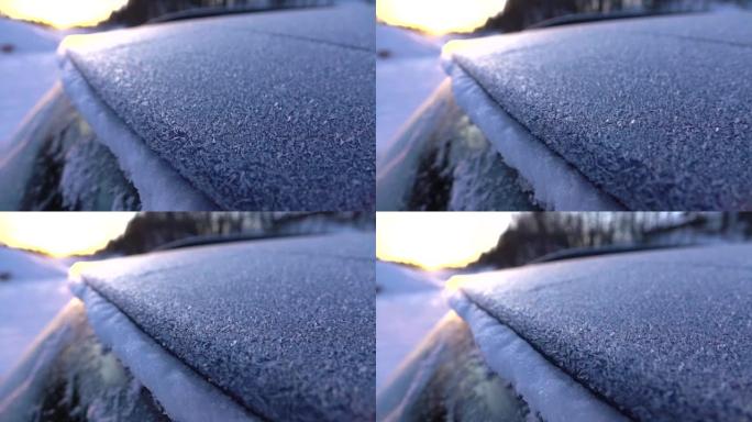 特写: 冰冷的汽车在寒冷的冬天日落时被早晨的霜冻和雪花覆盖